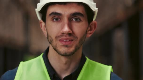 Portrét pohledného usměvavého inspektora ve speciálním oblečení pracující v továrně. Muž Inženýr nebo manažer v moderním skladu Při pohledu na kameru. Logistic Business Shipping and Delivery Concept - Záběry, video