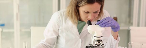 Γυναίκα επιστήμονας με μικροσκόπιο, δοκιμαστικούς σωλήνες, εργαστηριακά γυάλινα σκεύη και αντιδραστήρια που εξετάζει πολλά φρούτα και λαχανικά στο εργαστήριό της. Έννοια της έρευνας για τη διατροφή και την ποιότητα τροφίμων. - Φωτογραφία, εικόνα