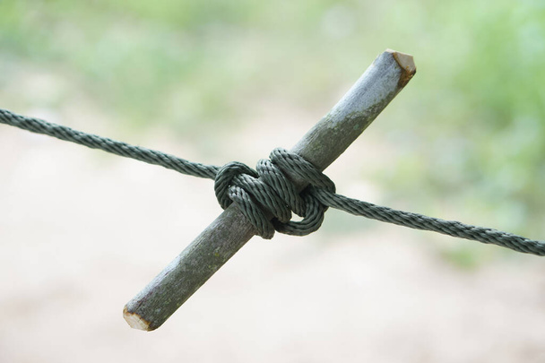 木の棒で縛られるロープの結び目を閉めて下さい. 日常生活の様々な目的に役立つコンセプト,タイピングノット. タイピングノットロープ教育援助. ロープによるサバイバルライフスキル.           - 写真・画像