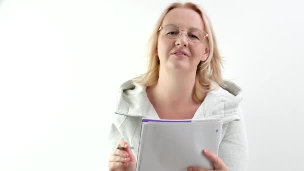 een journalist beschrijft de situatie met een bril op, een vrouw van middelbare leeftijd met een notitieblok luistert aandachtig naar het blonde haar. steekt haar vinger op - Video