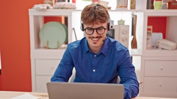 Молодий іспаномовний чоловік використовує ноутбук і навушники, сидячи на столі в їдальні
 - Кадри, відео