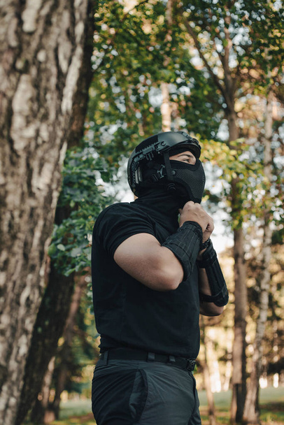 Airsoft soldier in the woods. Soldier taking down his equipment. Young man. - Photo, Image