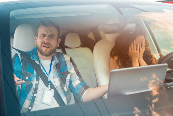 Frustrated young woman failed the driving test and covering her face with her hands, instructor sitting next to her in the car. Driving test, driver courses, exam concept - Photo, Image