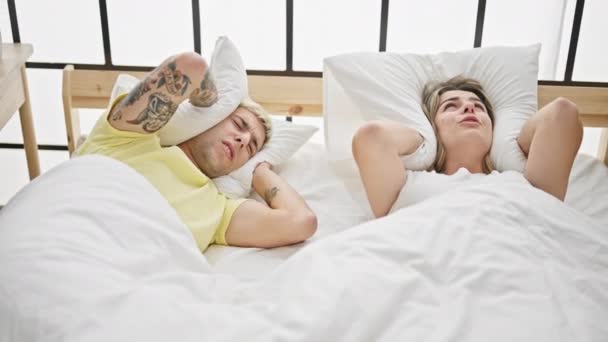 Hermosa pareja cubriendo oídos para el ruido acostado en la cama en el dormitorio - Imágenes, Vídeo
