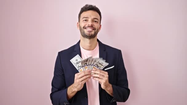 Молодий іспаномовний чоловік бізнесмен кидає долари в ефір над ізольованим рожевим тлом - Кадри, відео