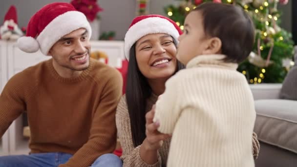 Pár és fia tartja dekoráció labda ül a padlón karácsonyfa otthon - Felvétel, videó