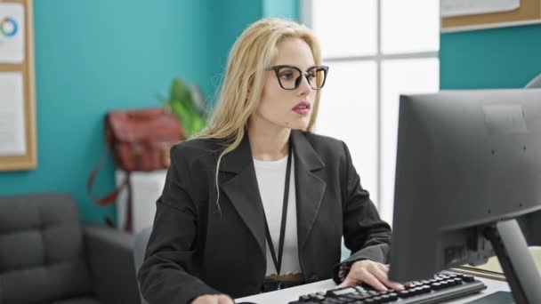 Joven mujer rubia trabajadora de negocios usando computadora celebrando en la oficina - Metraje, vídeo