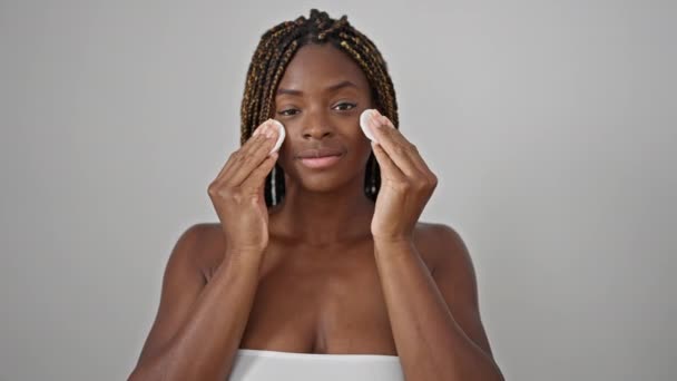 Mujer afroamericana sonriendo confiada cara de limpieza con almohadillas de algodón sobre fondo blanco aislado - Metraje, vídeo