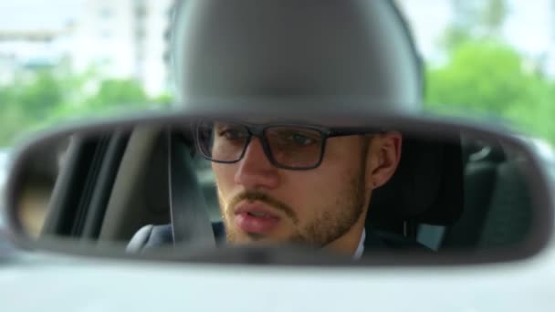 Rear view mirror. Close up of young man looking roadway while driving in the city. Transport, business, lifestyle and people concept. Slow motion - Footage, Video