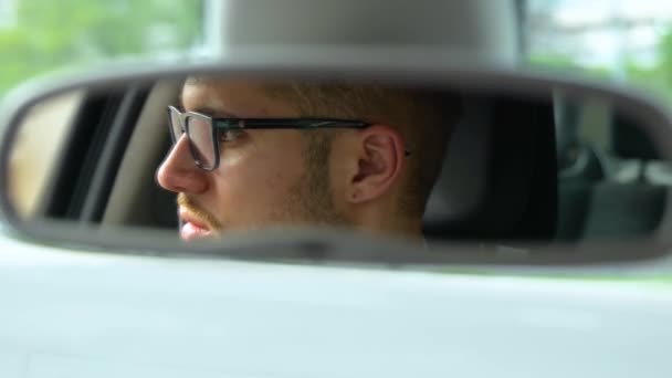 Riflessione del conducente maschile nello specchio retrovisore in auto durante la guida in città. Trasporti, affari, stile di vita e concetto di persone. Rallentatore - Filmati, video