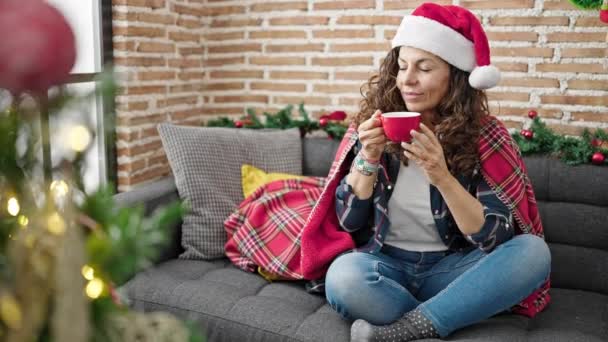 Mujer hispana de mediana edad bebiendo café celebrando la Navidad en casa - Metraje, vídeo