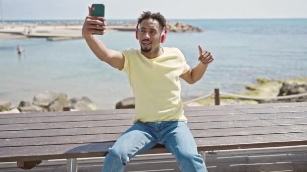 Αφροαμερικάνος άντρας ηχογραφεί βίντεο από smartphone που χορεύει στην παραλία - Πλάνα, βίντεο