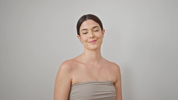 Νεαρή όμορφη ισπανόφωνη γυναίκα χαμογελά αυτοπεποίθηση συγκινητικό πρόσωπο πάνω από απομονωμένο λευκό φόντο - Πλάνα, βίντεο