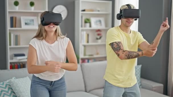 Όμορφο ζευγάρι παίζει χορό video game χρησιμοποιώντας γυαλιά εικονικής πραγματικότητας στο σπίτι - Πλάνα, βίντεο