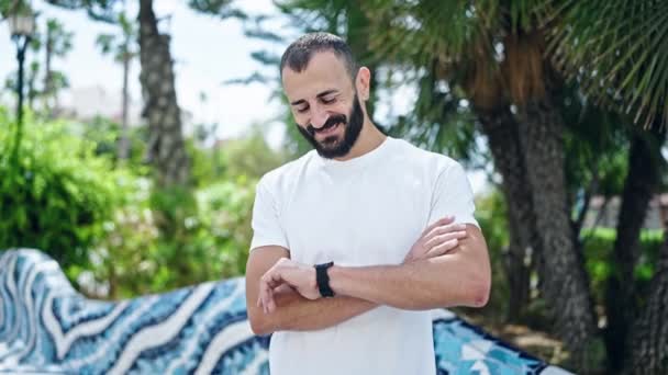 Jonge Spaanse man glimlacht vol vertrouwen wijzend om te kijken naar park - Video