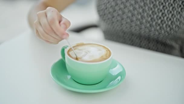 Νεαρή ξανθιά γυναίκα ανακατεύει τον καφέ στη βεράντα του καφενείου - Πλάνα, βίντεο