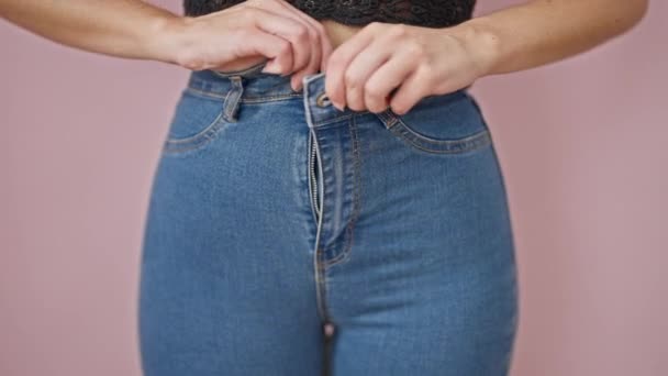 Young blonde woman button jeans up standing over isolated pink background - Footage, Video