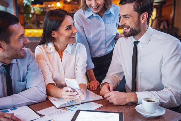 Mensen uit het bedrijfsleven gebruikt gadgets, praten en lachen terwijl u werkt in café - Foto, afbeelding