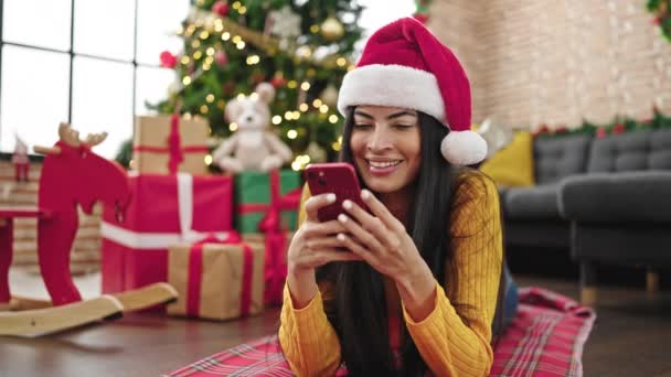 Joven mujer hispana hermosa celebrando la Navidad con el teléfono inteligente en casa - Metraje, vídeo