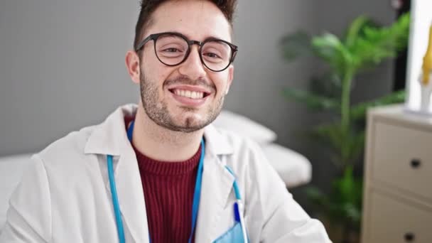 Jovem hispânico homem médico sorrindo confiante na clínica - Filmagem, Vídeo