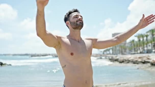 Genç İspanyol turist mayo giyiyor. Kumsalda kolları açık nefes alıyor. - Video, Çekim