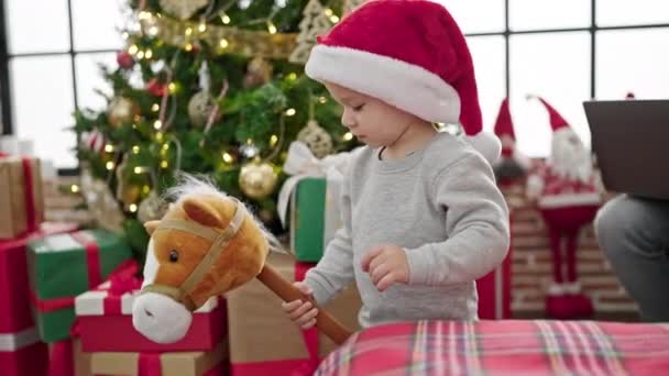 caucasico bambino giocare con natale presente dondolo cavallo giocattolo a casa - Filmati, video