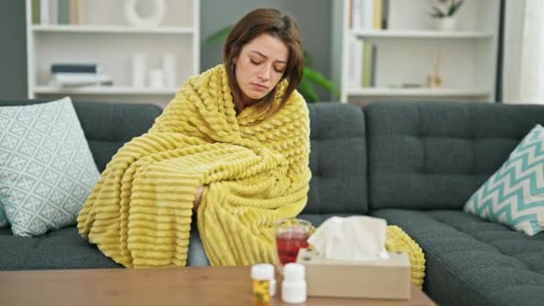 Joven mujer hispana hermosa sentada en el sofá enferma usando tejido en casa - Imágenes, Vídeo