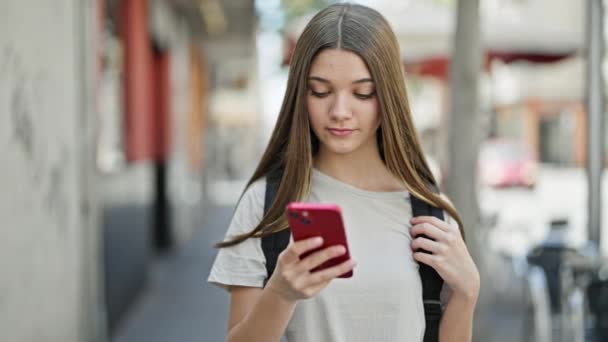 Mladá krásná dívka student nosit batoh pomocí smartphone na ulici - Záběry, video