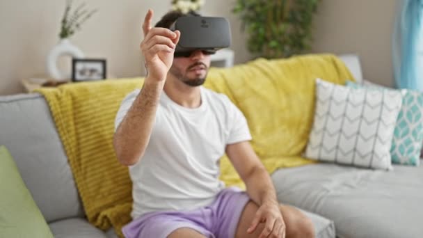 Νεαρός Άραβας παίζει βιντεοπαιχνίδι με γυαλιά εικονικής πραγματικότητας στο σπίτι - Πλάνα, βίντεο