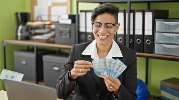 Молодая красивая латиноамериканка, деловая женщина, кидающая чилийские песо, улыбаясь в офисе - Кадры, видео