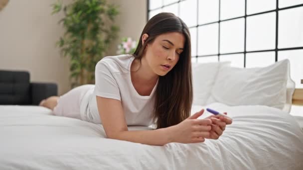 Junge schöne hispanische Frau mit Schwangerschaftstest gestresst im Schlafzimmer - Filmmaterial, Video