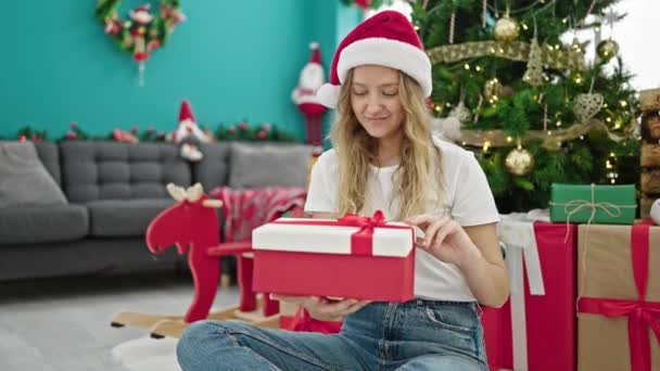 Joven mujer rubia desempacando regalo celebrando la Navidad en casa - Metraje, vídeo