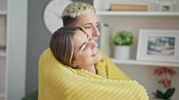 Hermosa pareja cubriendo con manta abrazándose besándose en casa - Metraje, vídeo