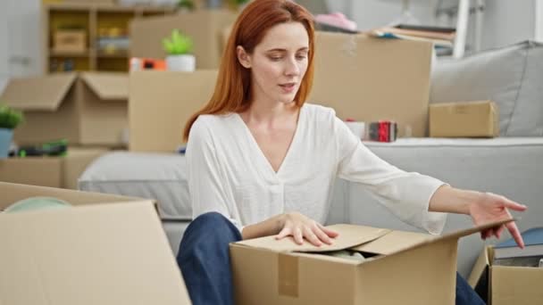 Jeune rousse femme emballage boîte en carton à la nouvelle maison - Séquence, vidéo