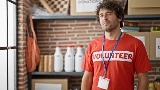 Νεαρός Ισπανός που φοράει στολή εθελοντή στέκεται με σοβαρό πρόσωπο στο φιλανθρωπικό κέντρο - Πλάνα, βίντεο