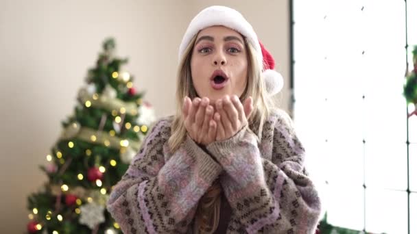 jong blond vrouw staan door christmas boom zoenen thuis - Video