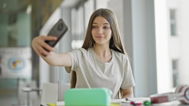 Giovane bella ragazza studente fare selfie da smartphone sorridente alla biblioteca - Filmati, video