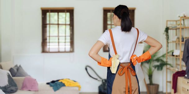 Kobieta gospodyni, prace domowe Azji młoda kobieta stoją i patrząc salon w domu. - Zdjęcie, obraz