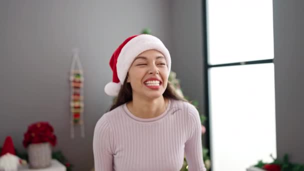 jong mooi latino vrouw zwaaien naar de camera door kerstboom thuis - Video
