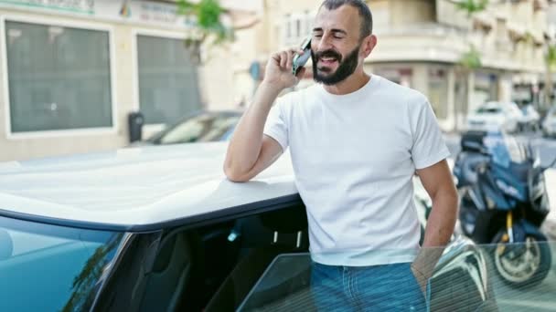 jonge latino man praten op smartphone leunend op de auto op straat - Video