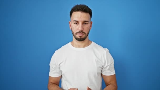 Mladý arabsky muž usmívá sebevědomě mluví přes izolované modré pozadí - Záběry, video