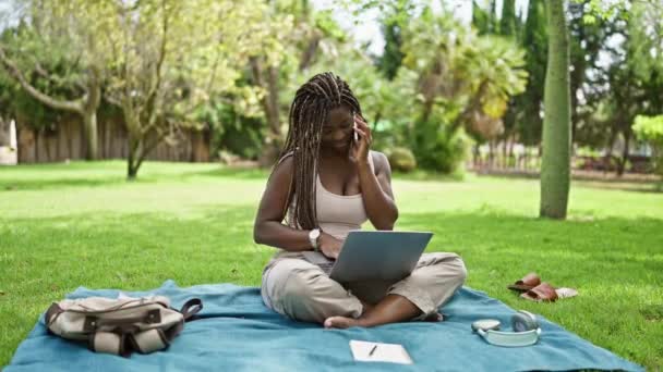Afrikkalainen amerikkalainen nainen opiskelija käyttää laptop puhuu älypuhelimella kampuksella yliopistossa - Materiaali, video