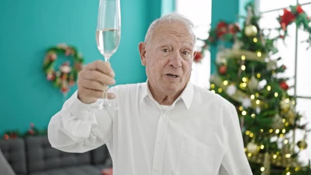 Ένας γκριζομάλλης γιορτάζει τα Χριστούγεννα πίνοντας σαμπάνια μιλώντας στο σπίτι. - Πλάνα, βίντεο