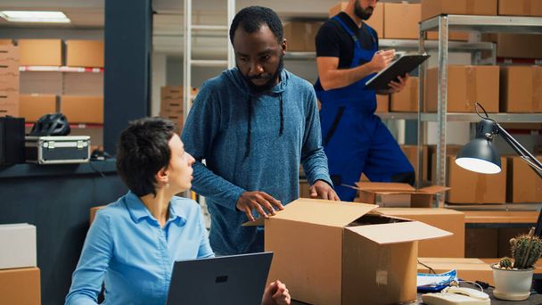 Small business owners doing quality control before shipping products order, packing merchandise in cardboard boxes. Workers preparing delivery and shipment in warehouse storage room. - Photo, image