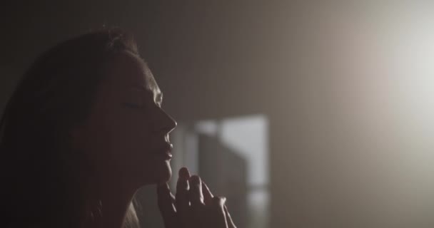 кишеньковий знімок молодої жінки-музикантки, що сидить у темній кімнаті, освітлений тьмяним сонячним світлом, що торкається підборіддя, маючи натхнення та композицію музики - Кадри, відео