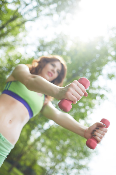 woman with dumbbells in park - Photo, image