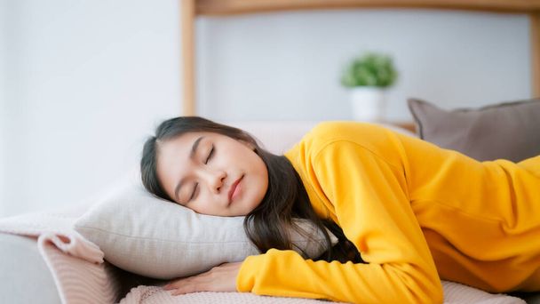 Азиатка отдыхает дома на диване, чувствует себя измотанной после работы, не хватает энергии, или переутомленной, слишком уставшей, и не хватает мотивации - Фото, изображение