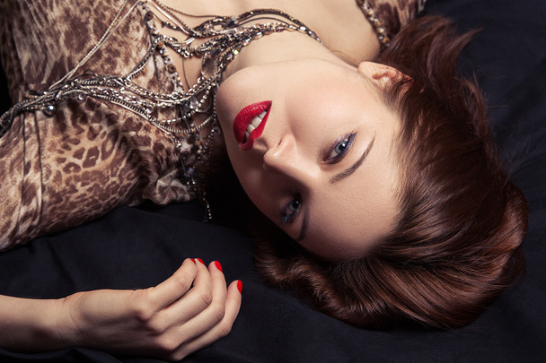 High fashion look. Glamor closeup portrait of beautiful sexy stylish woman model lying on black bed with bright makeup, with red lips, with perfect clean on bed - Фото, зображення