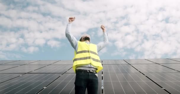 文書を持つ幸せな技術者は成功にあなたの手を上げる。完成したプロジェクト。幸せよ。太陽電池は将来の重要な再生可能エネルギーになります. - 映像、動画