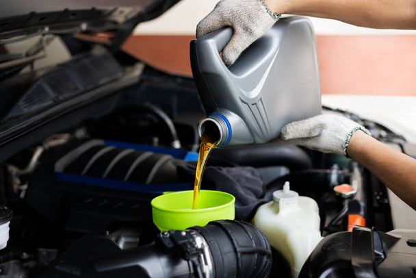 Verser le lubrifiant de voiture d'une bouteille grise sur le fond du moteur. Service de vidange d'huile, atelier de réparation automobile - Photo, image
